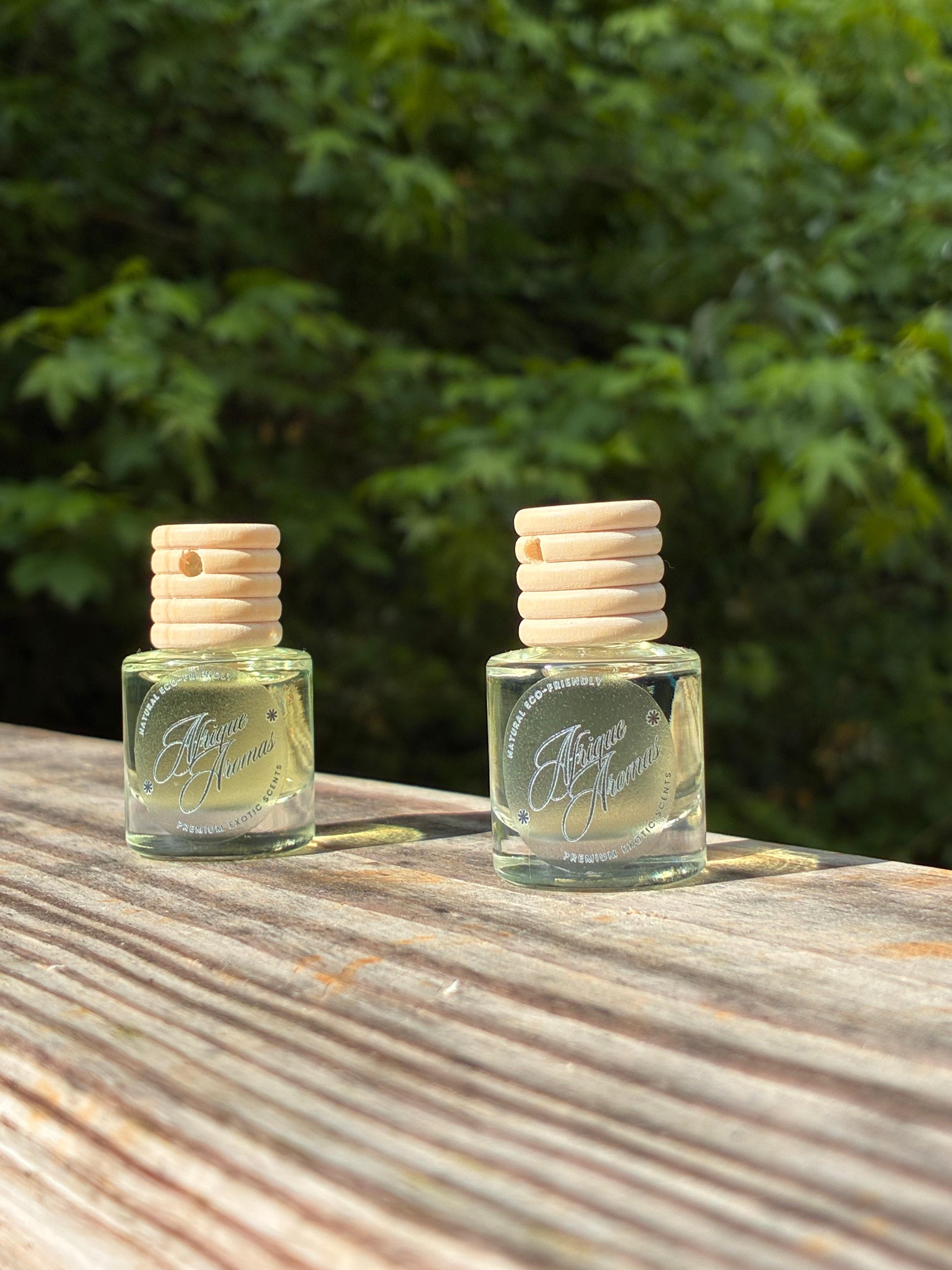 Two small glass bottles with wooden caps on a wooden surface with a blurred green background