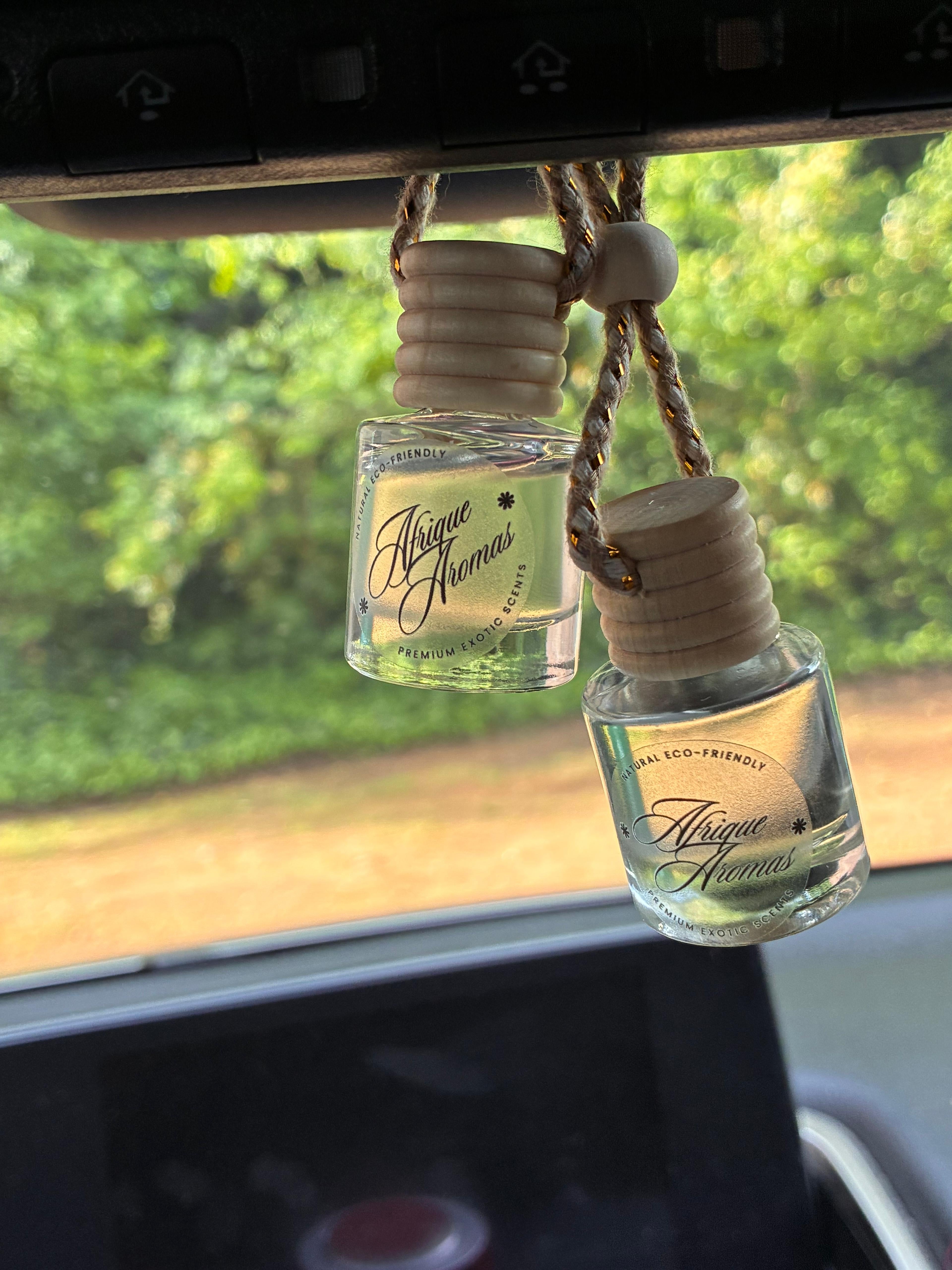 Two small glass bottles with wooden caps hanging from a car's rearview mirror.